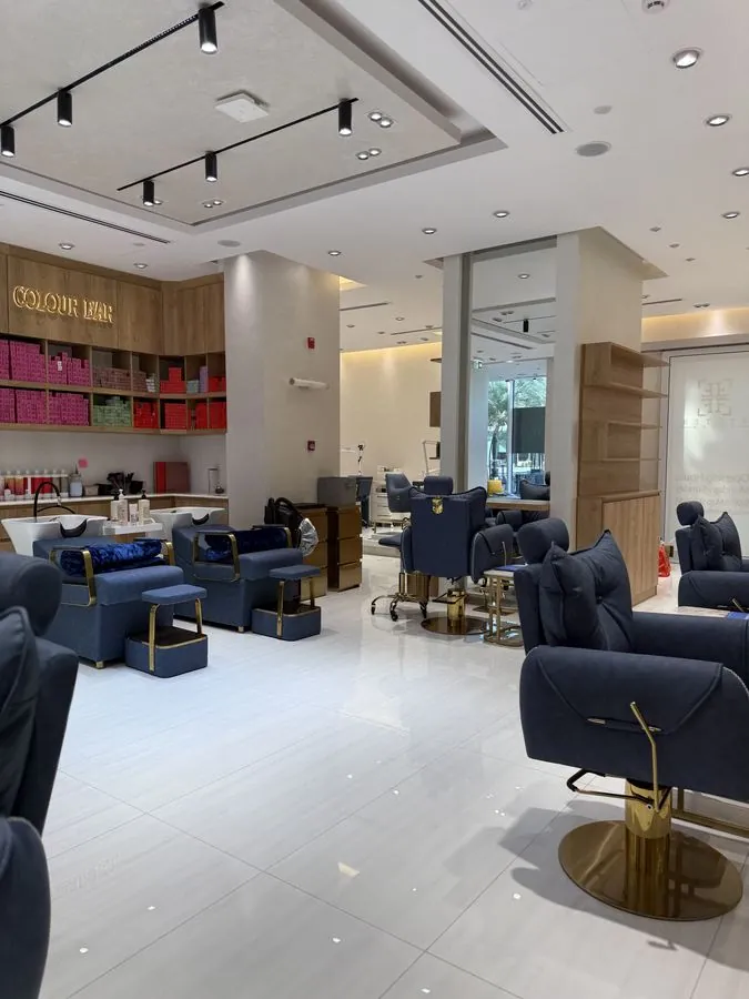 The main salon floor — navy and gold styling chairs and pedicure thrones